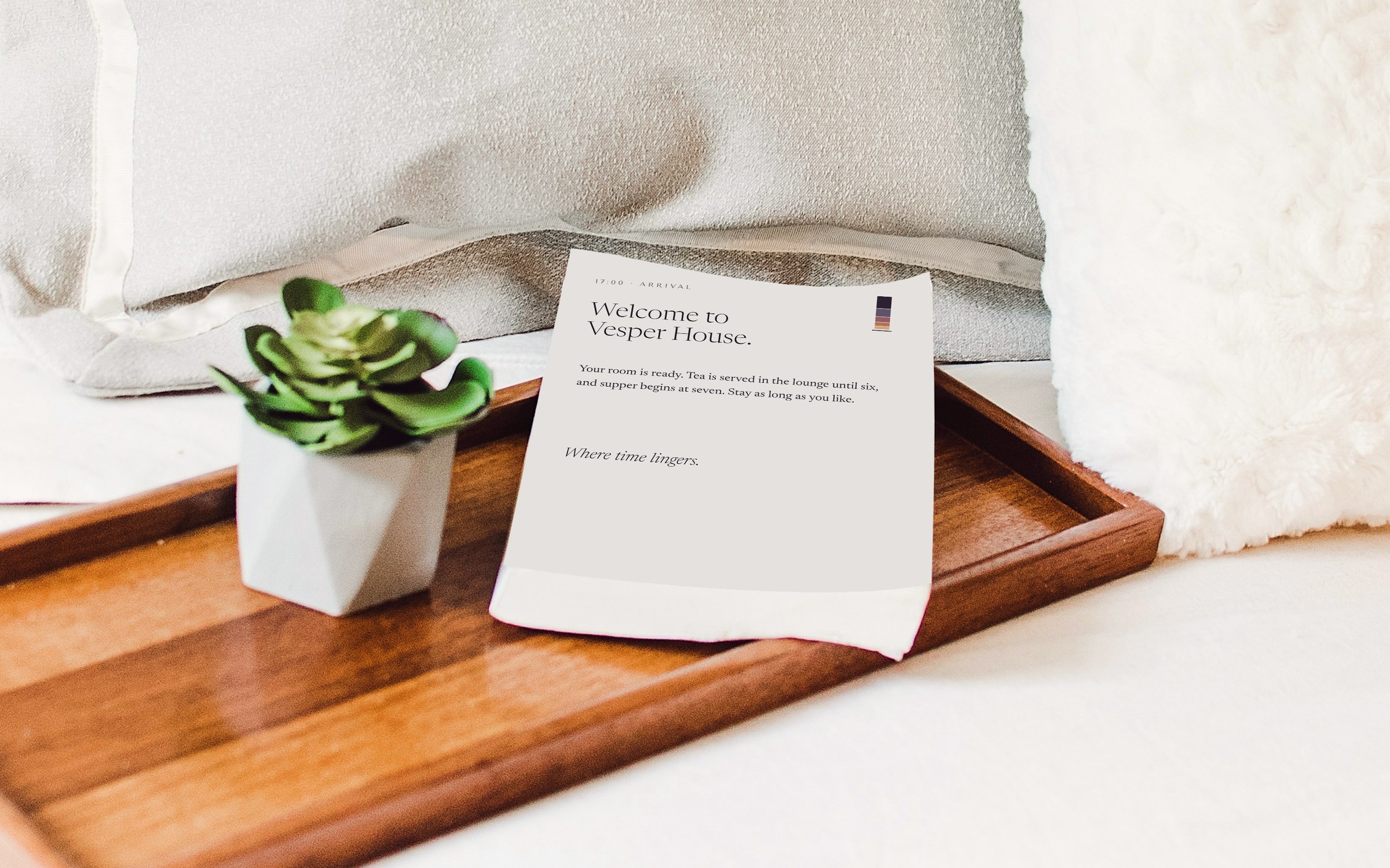 A Vesper House welcome card on a wooden tray on a made bed, reading Welcome to Vesper House and Where time lingers.