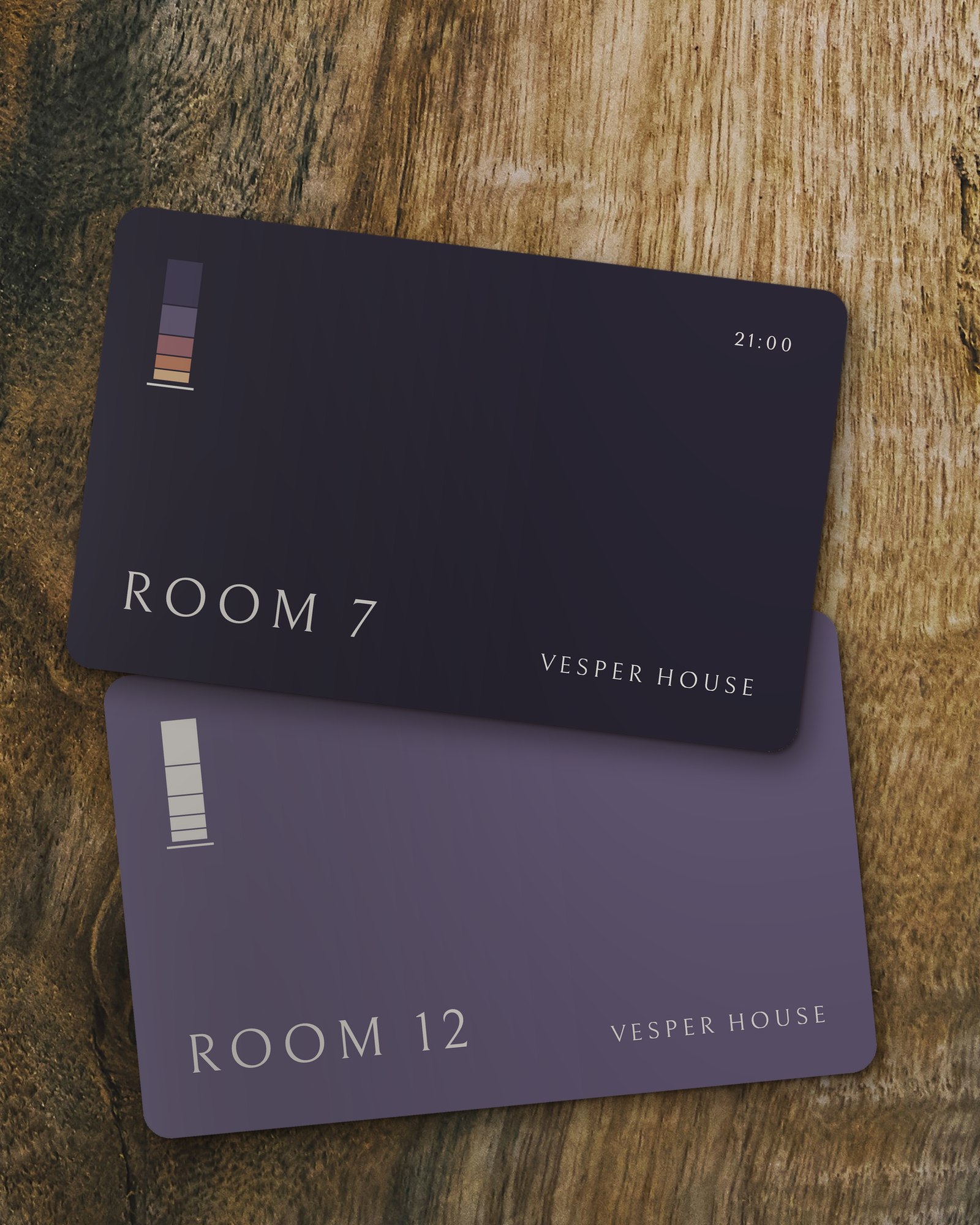 Two Vesper House room key cards on walnut, Room 7 in night blue and Room 12 in heather, each with the window symbol.